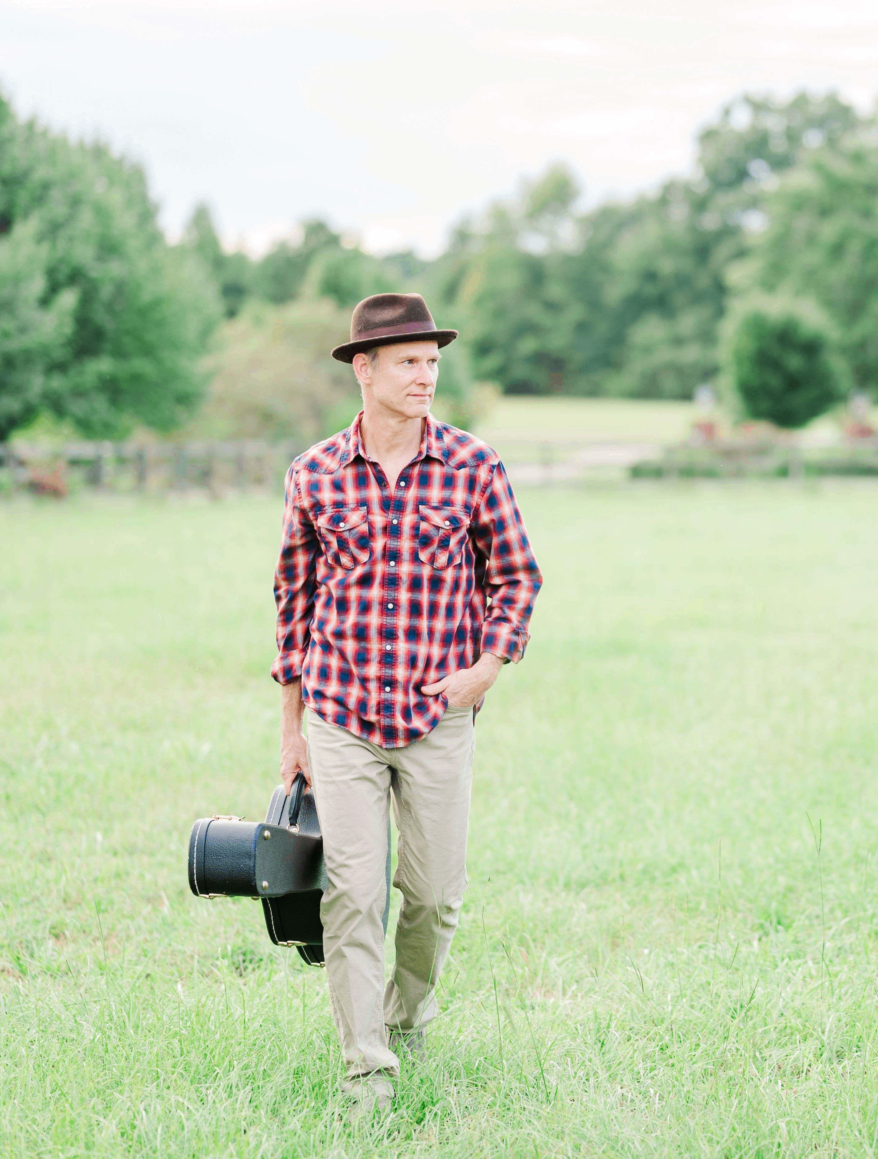 a man holding a camera in a grassy field