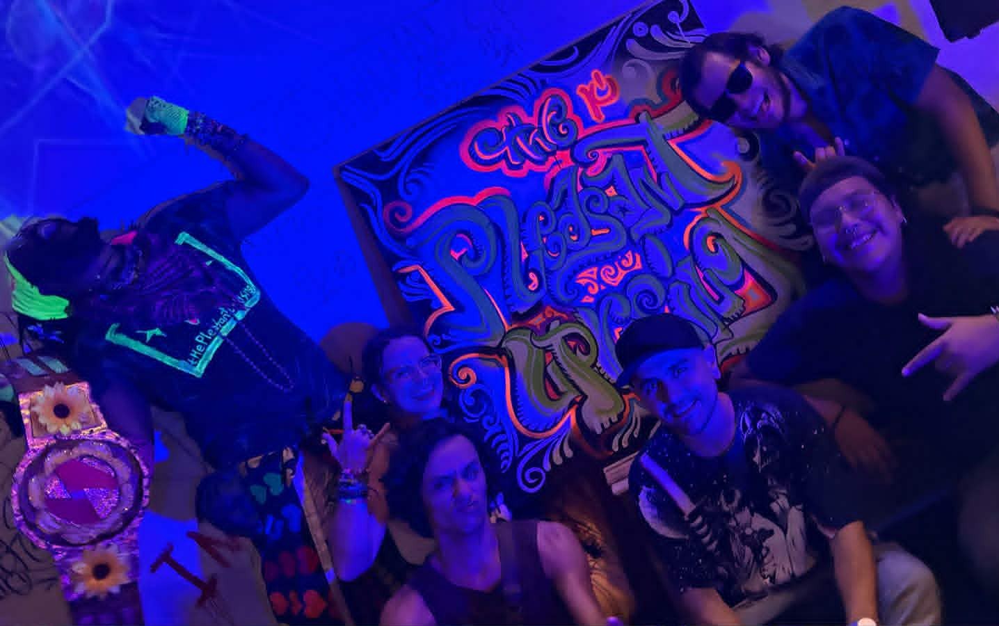 a group of people posing in front of a neon sign