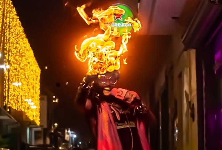 a man with a flame on his head walking down the street