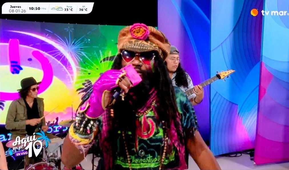 a man in a colorful outfit singing on a television