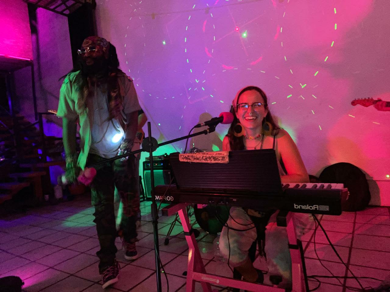 a woman with dreadlocks and a keyboard in front of a colorful light