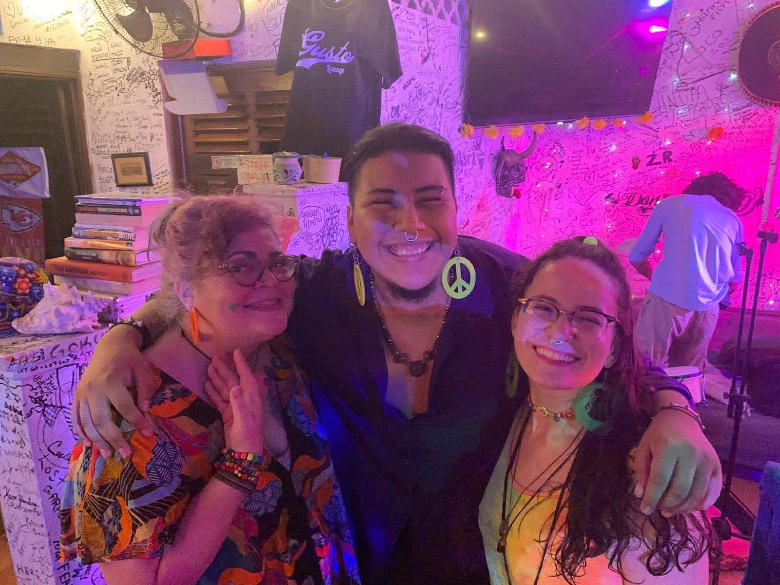 three women and a man posing for a photo in a bar