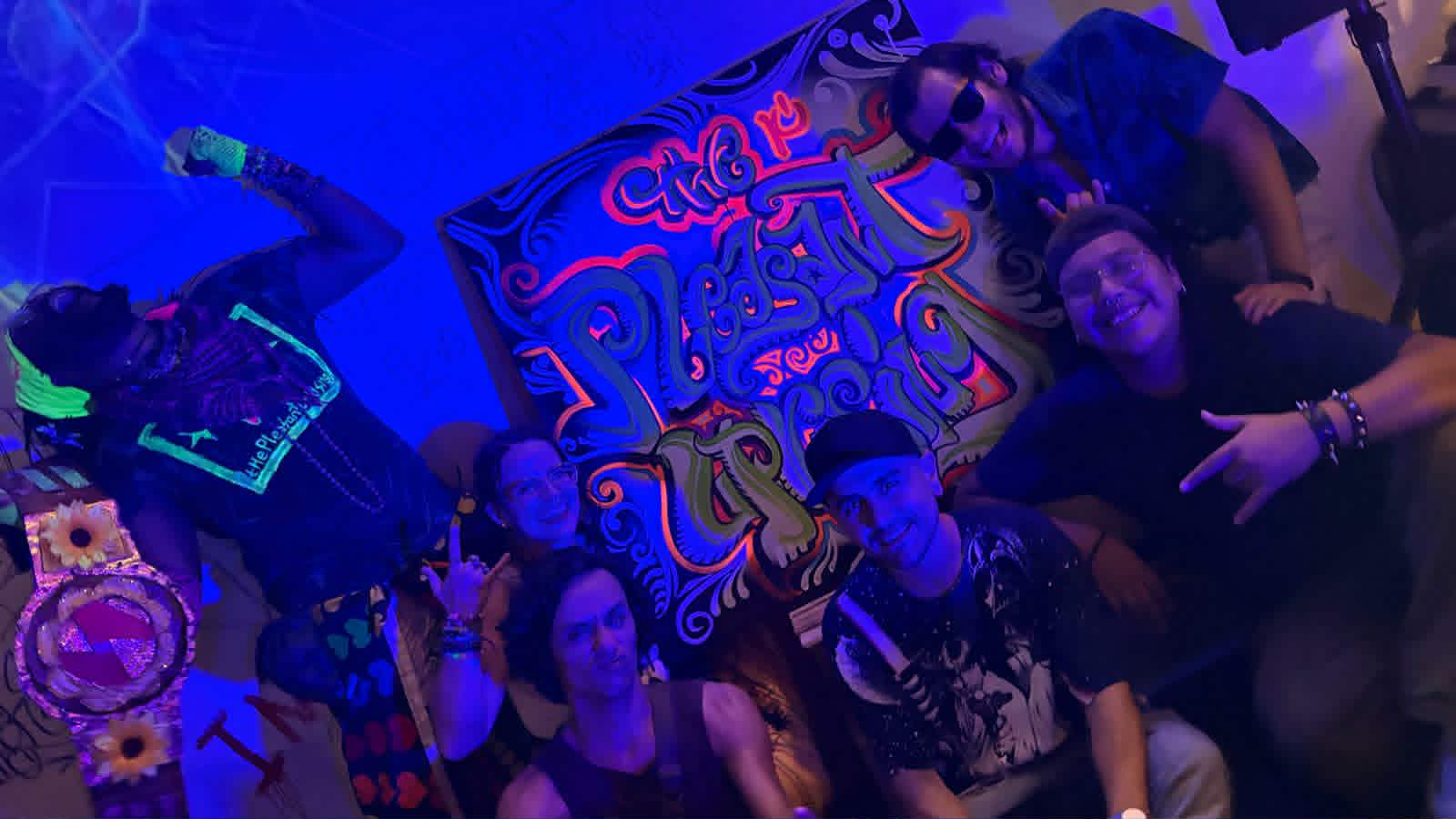 a group of people posing in front of a neon sign
