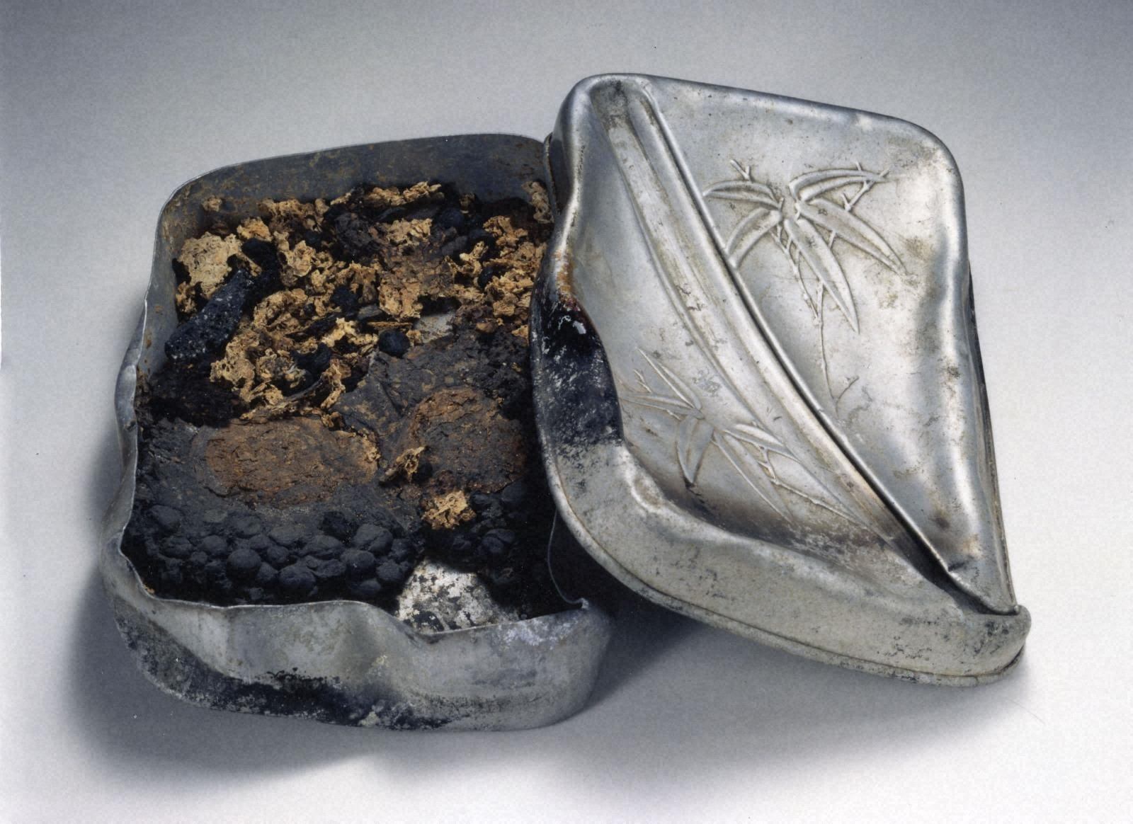 a silver tin with a small amount of dirt in it