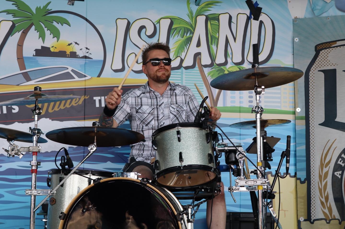 a man in sunglasses playing drums at a festival
