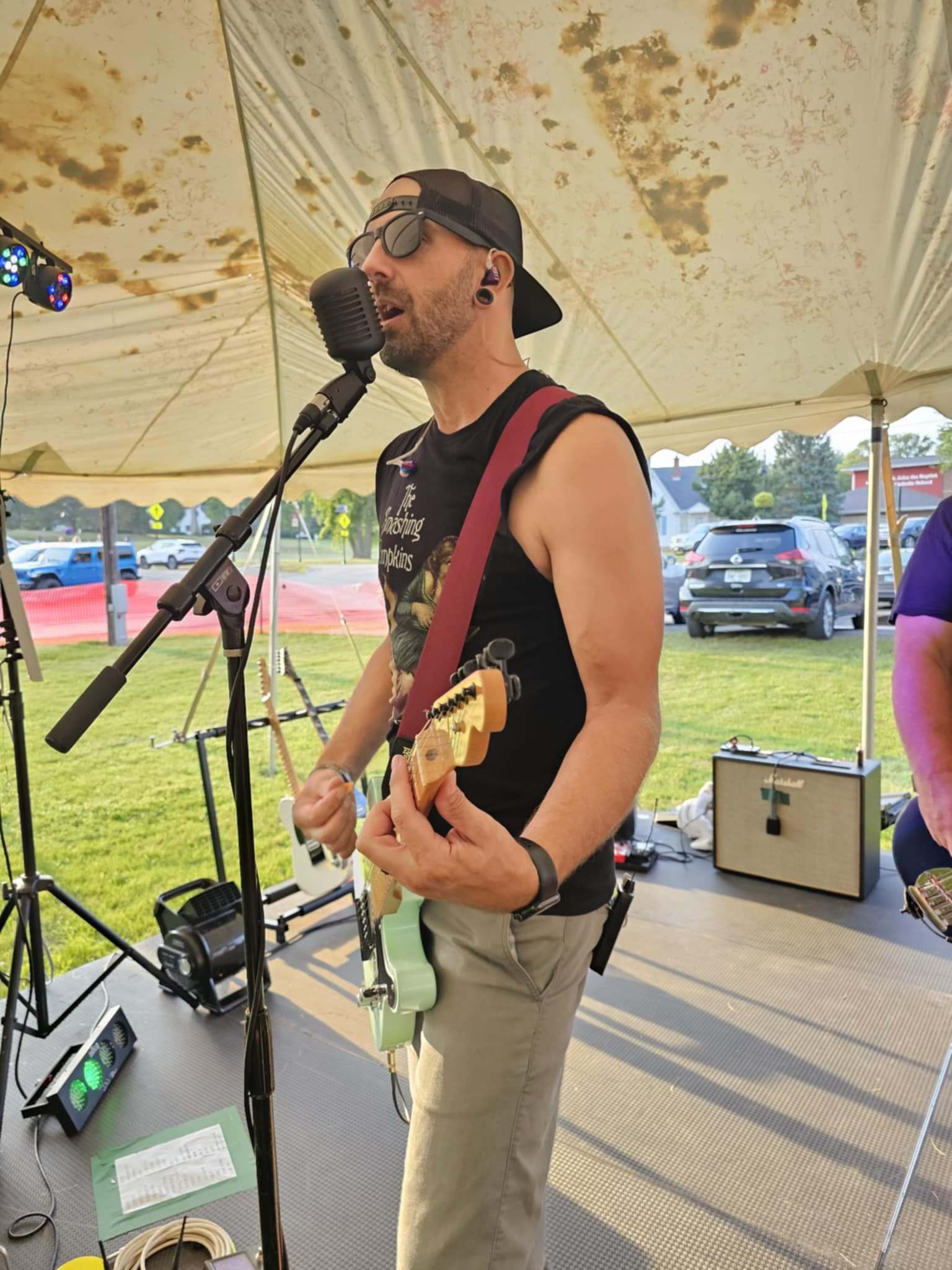 a man in a hat is playing guitar in front of a tent