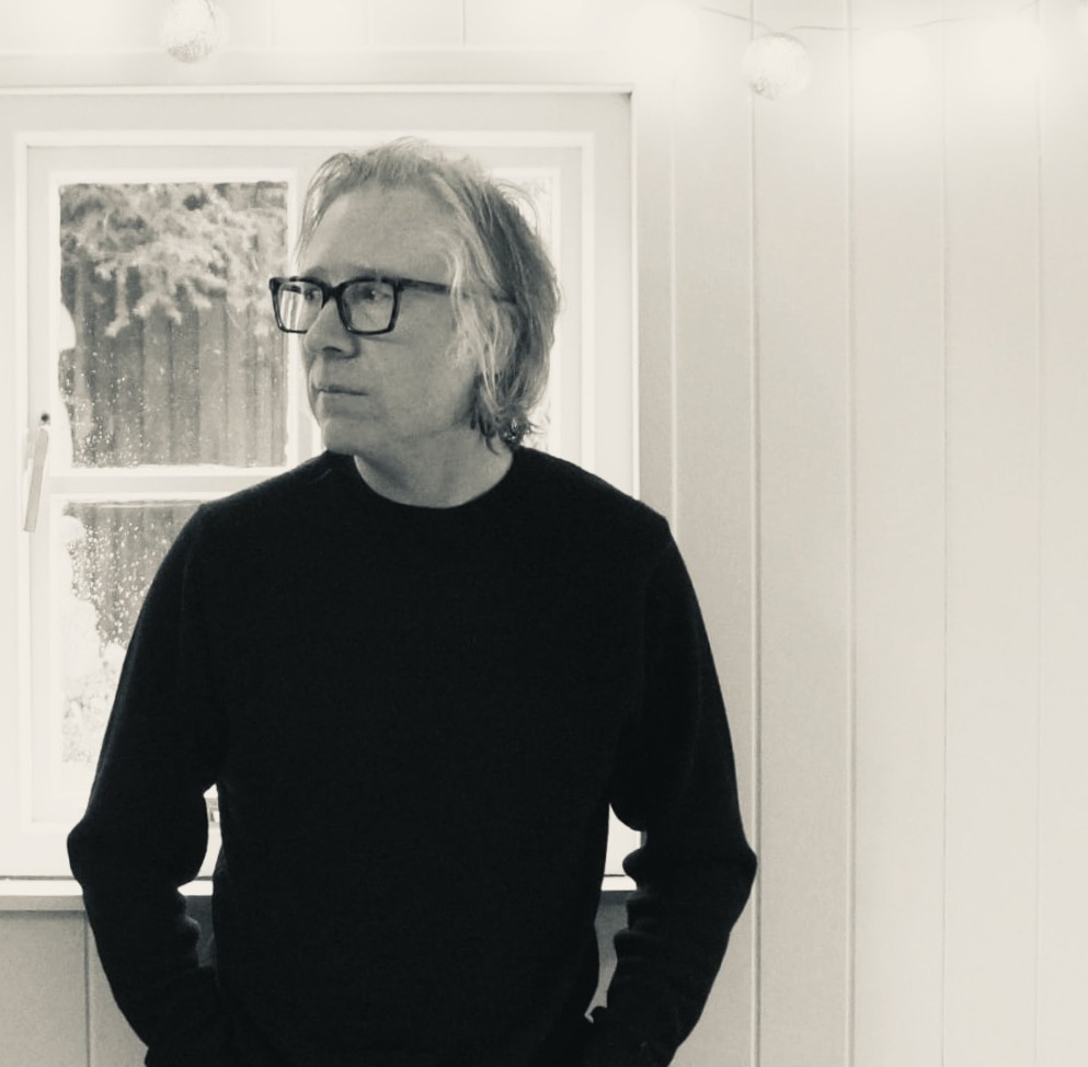 a man in glasses standing in front of a window