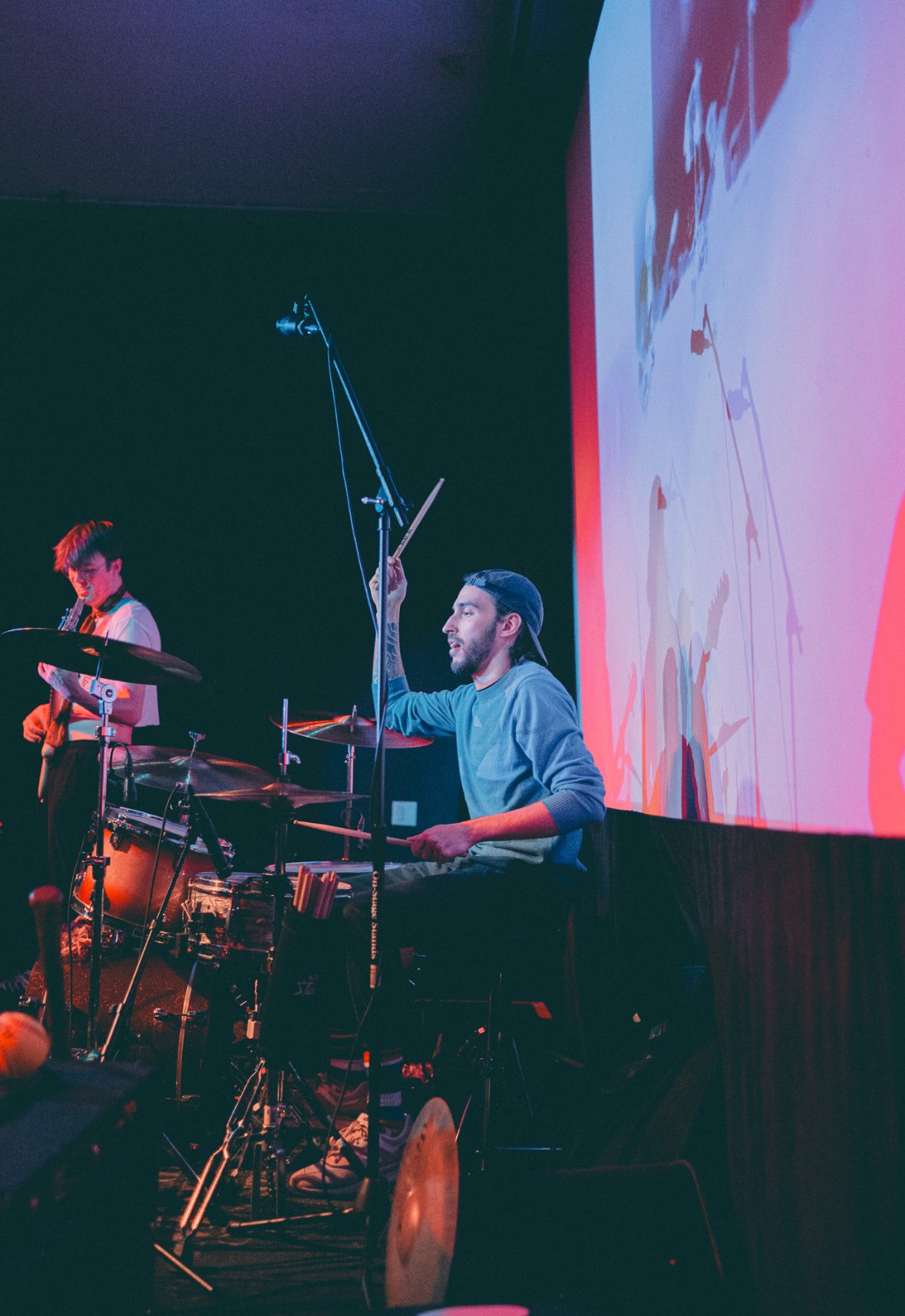 a man is playing drums in front of a projection screen