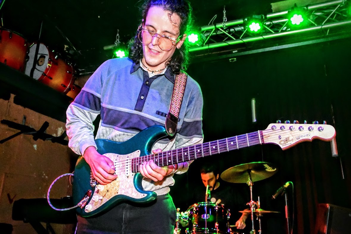 a young man playing an electric guitar on stage