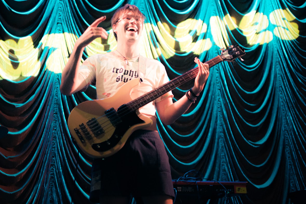 a man is playing a guitar in front of a curtain