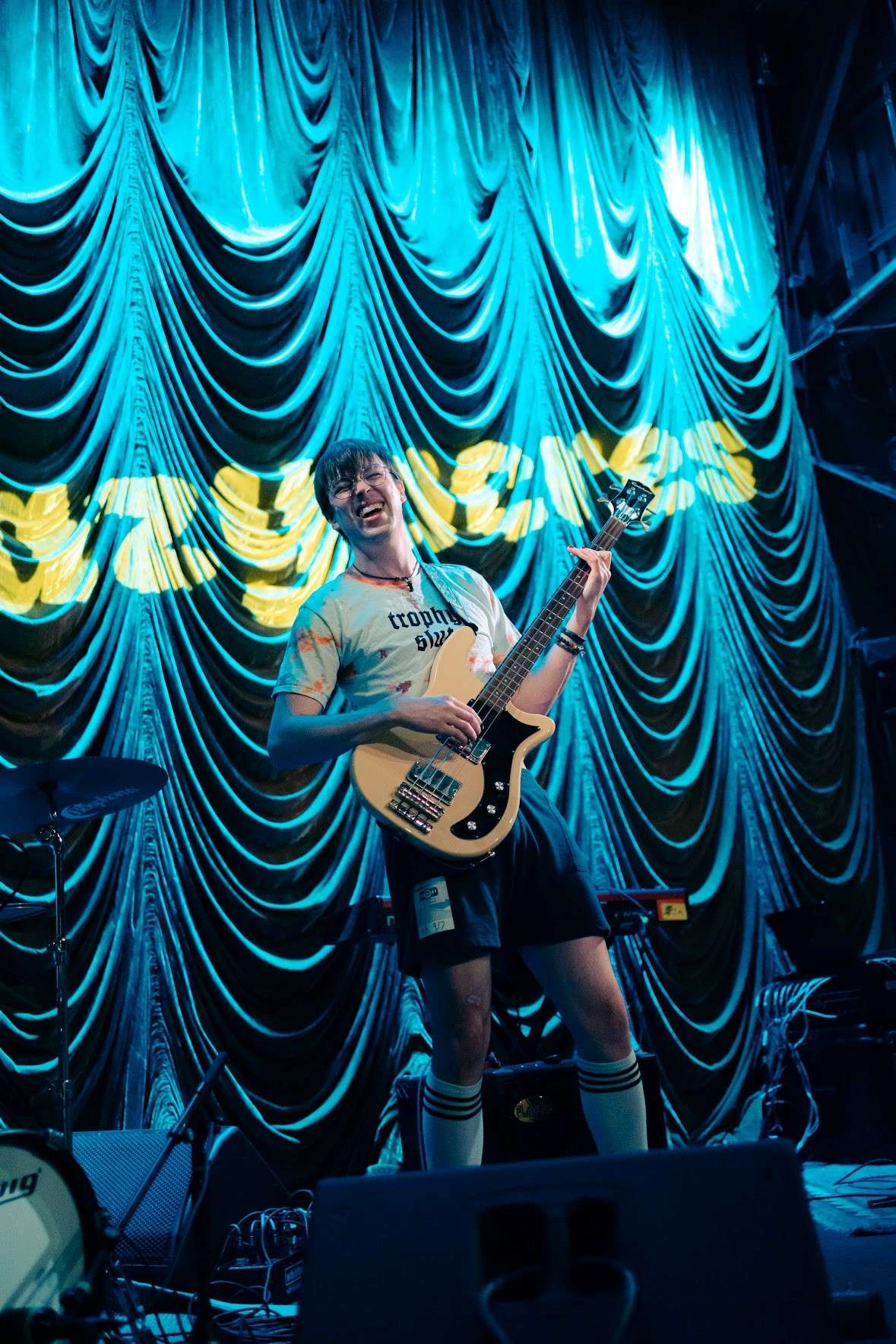 a man playing a guitar on stage in front of a curtain
