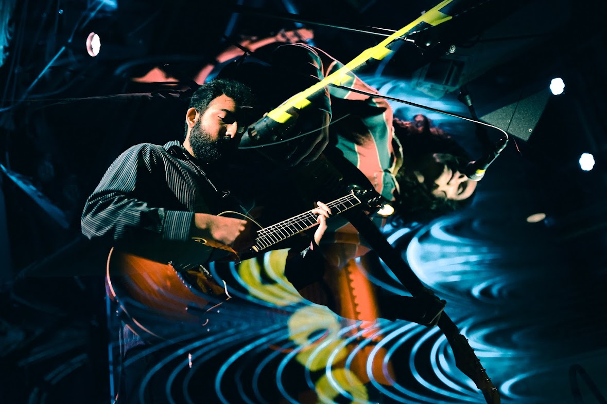 two men playing guitar in a dark room
