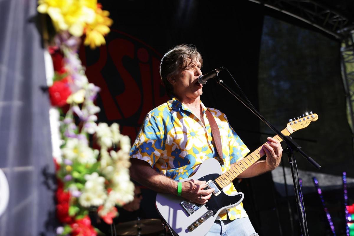 a man playing a guitar in front of flowers