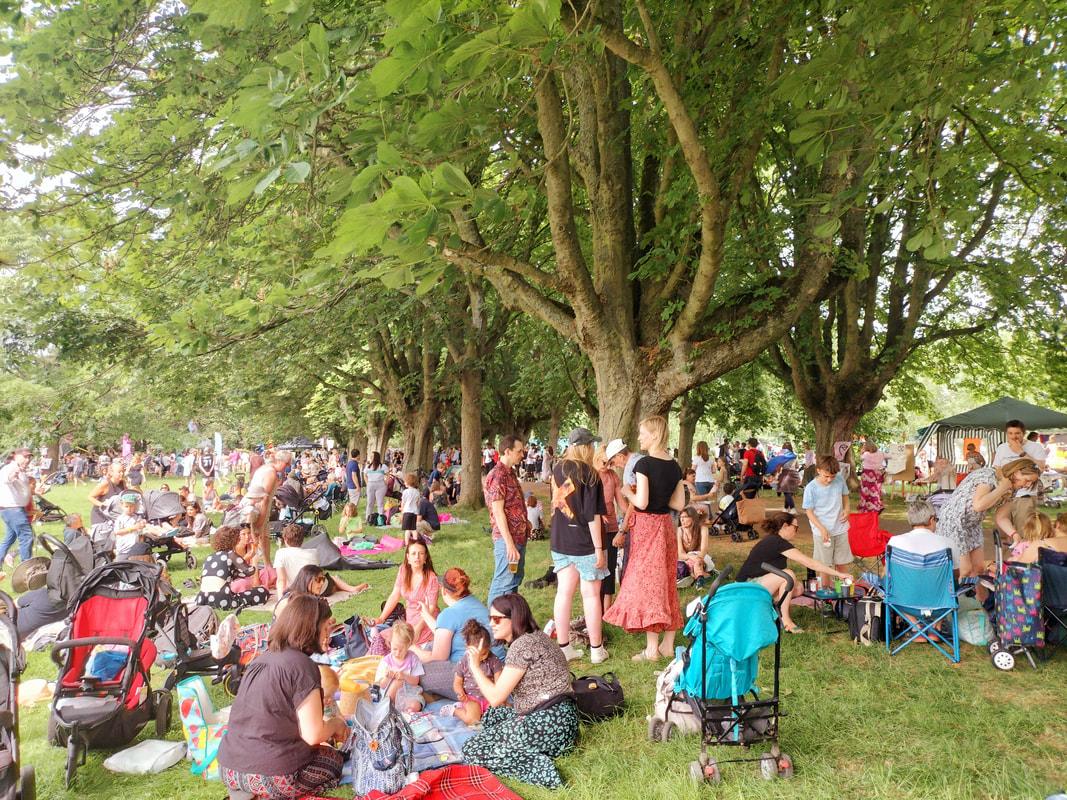 a crowd of people sitting under trees in a park