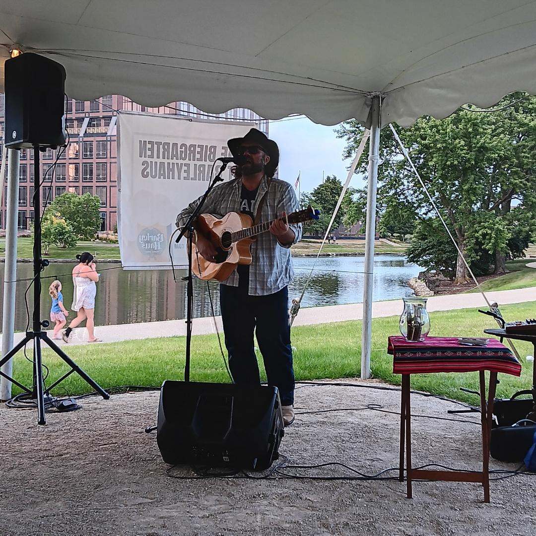 a man playing an acoustic guitar in front of a tent