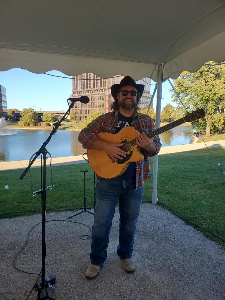 a man in a cowboy hat playing an acoustic guitar