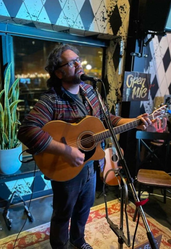 a man playing an acoustic guitar in front of a microphone