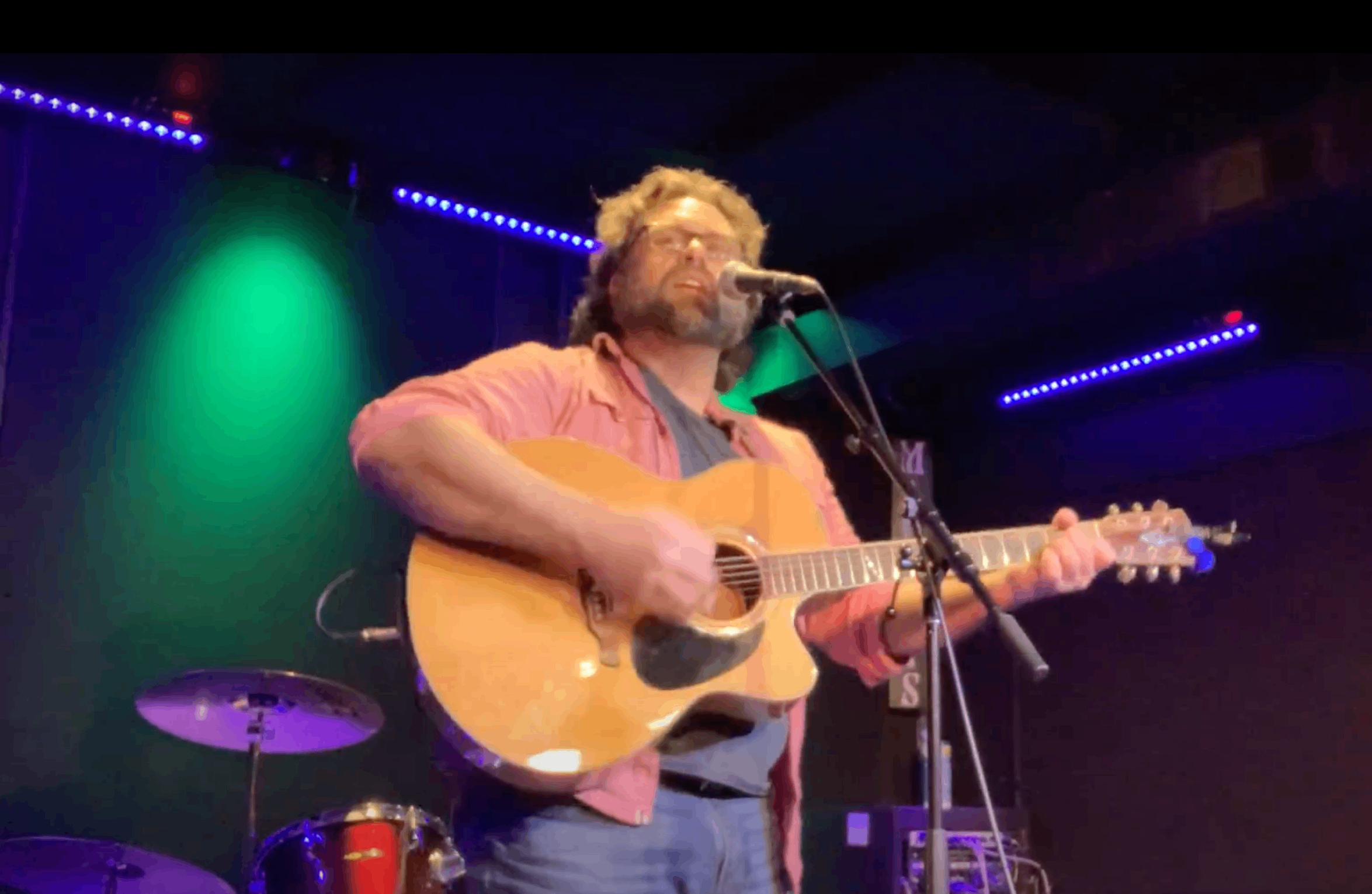 a man playing an acoustic guitar in front of a microphone