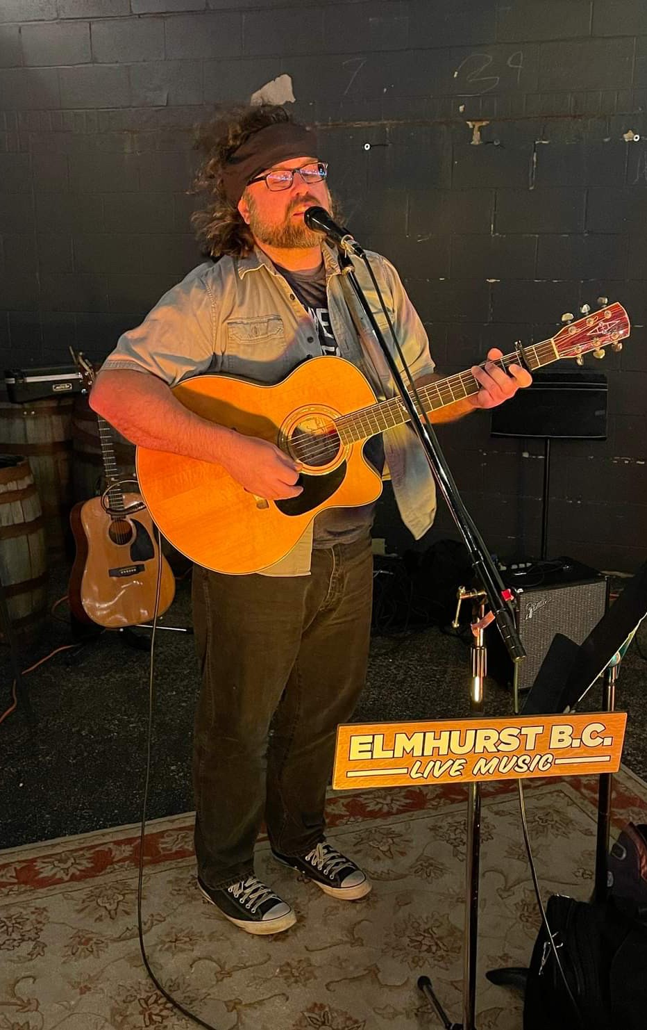 a man playing an acoustic guitar in front of a microphone