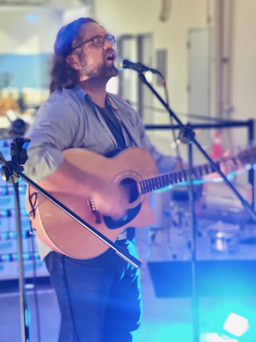 a man playing an acoustic guitar in front of a microphone