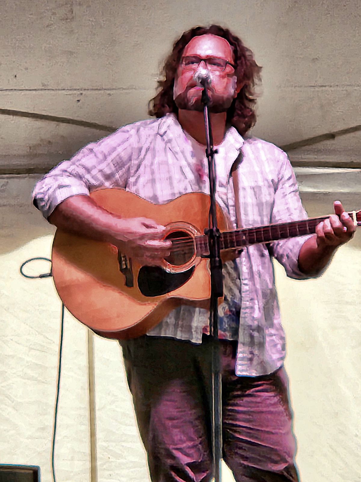 a man playing an acoustic guitar in front of a microphone