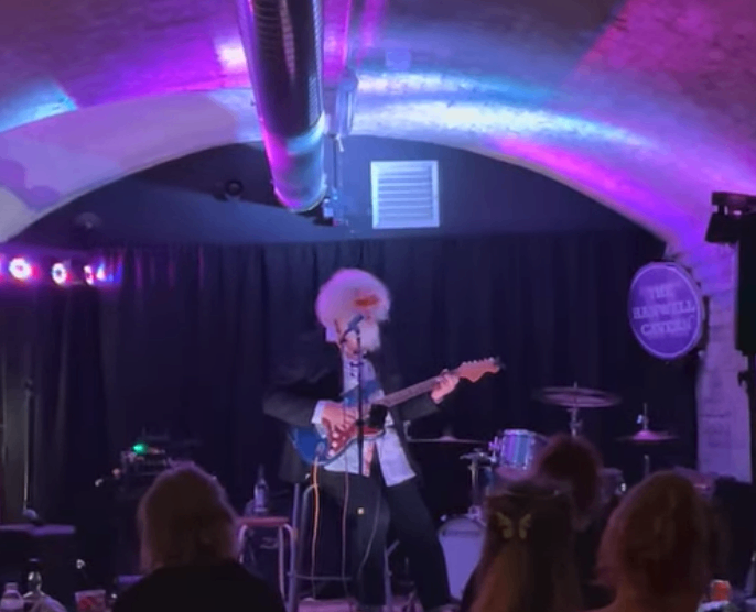 a man playing guitar on stage in a dark room