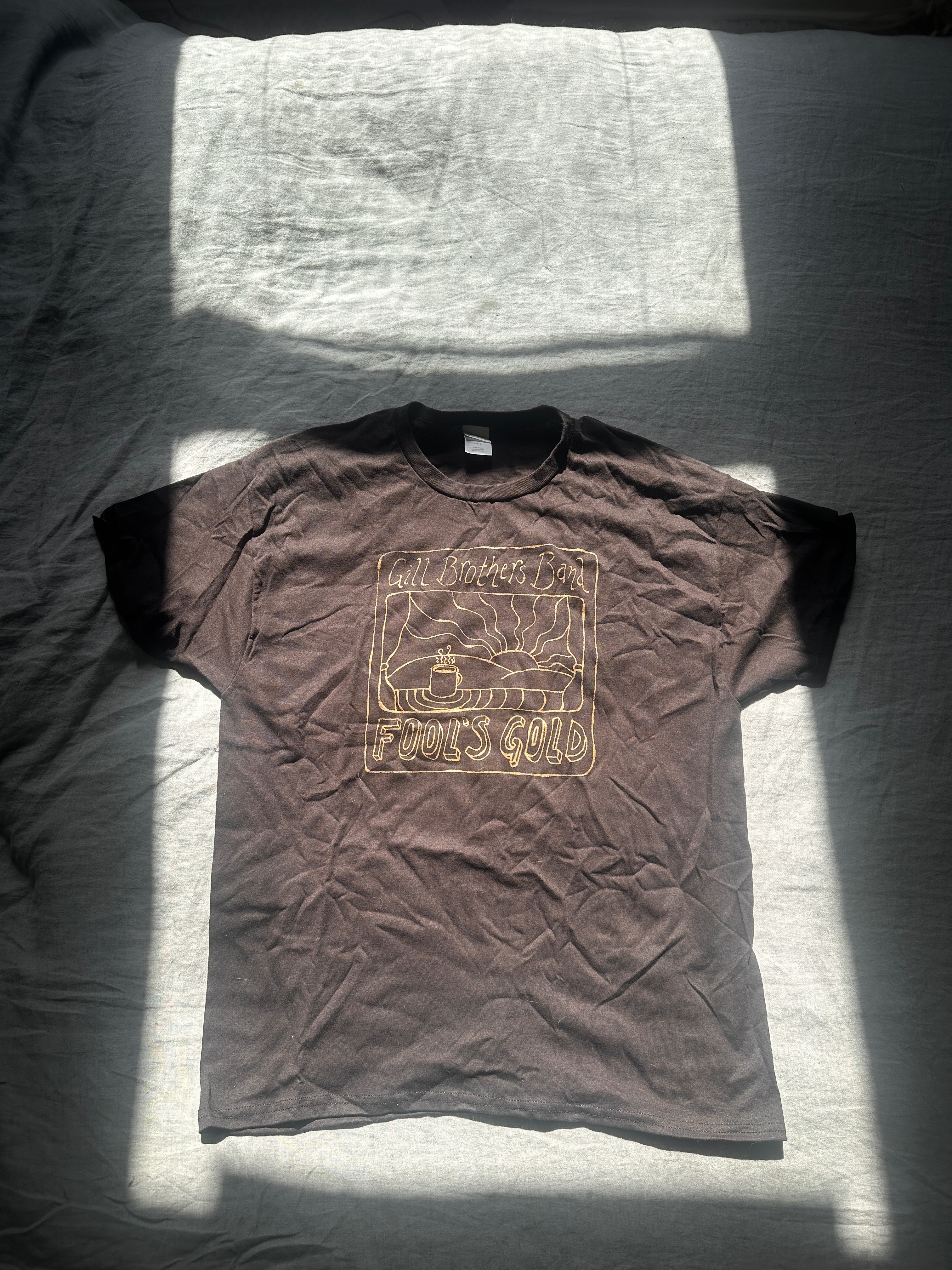 a brown t - shirt on a bed with the sun shining on it