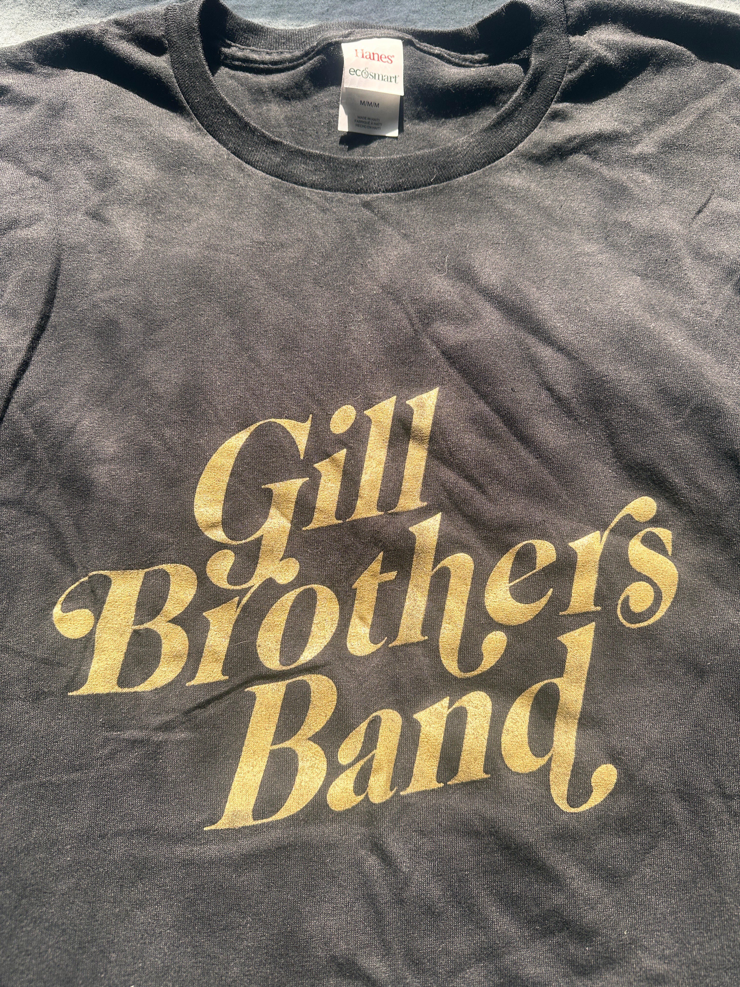 a black t - shirt with gold lettering that says gill brothers band
