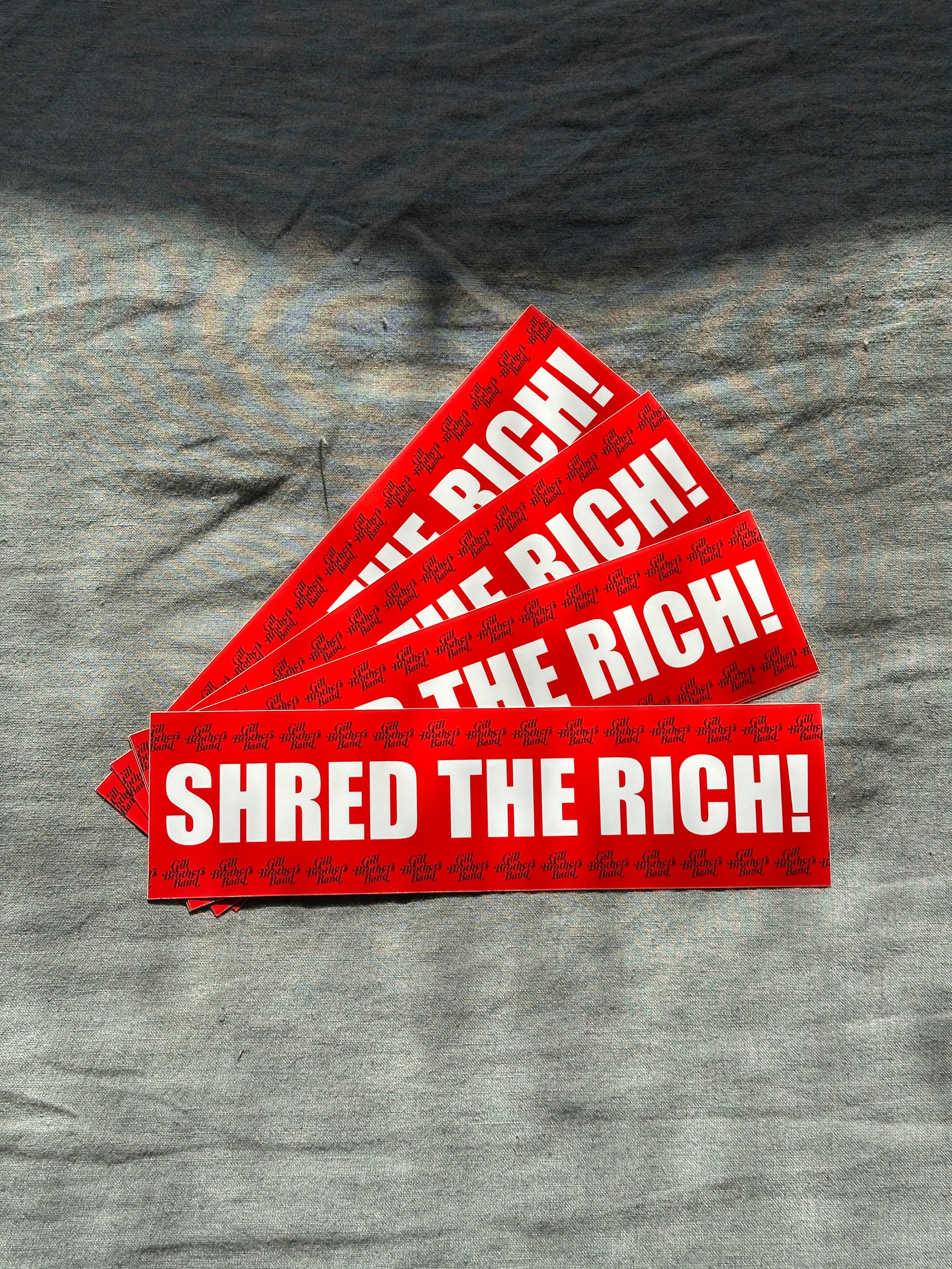 a red sticker with the words shred the rich on it