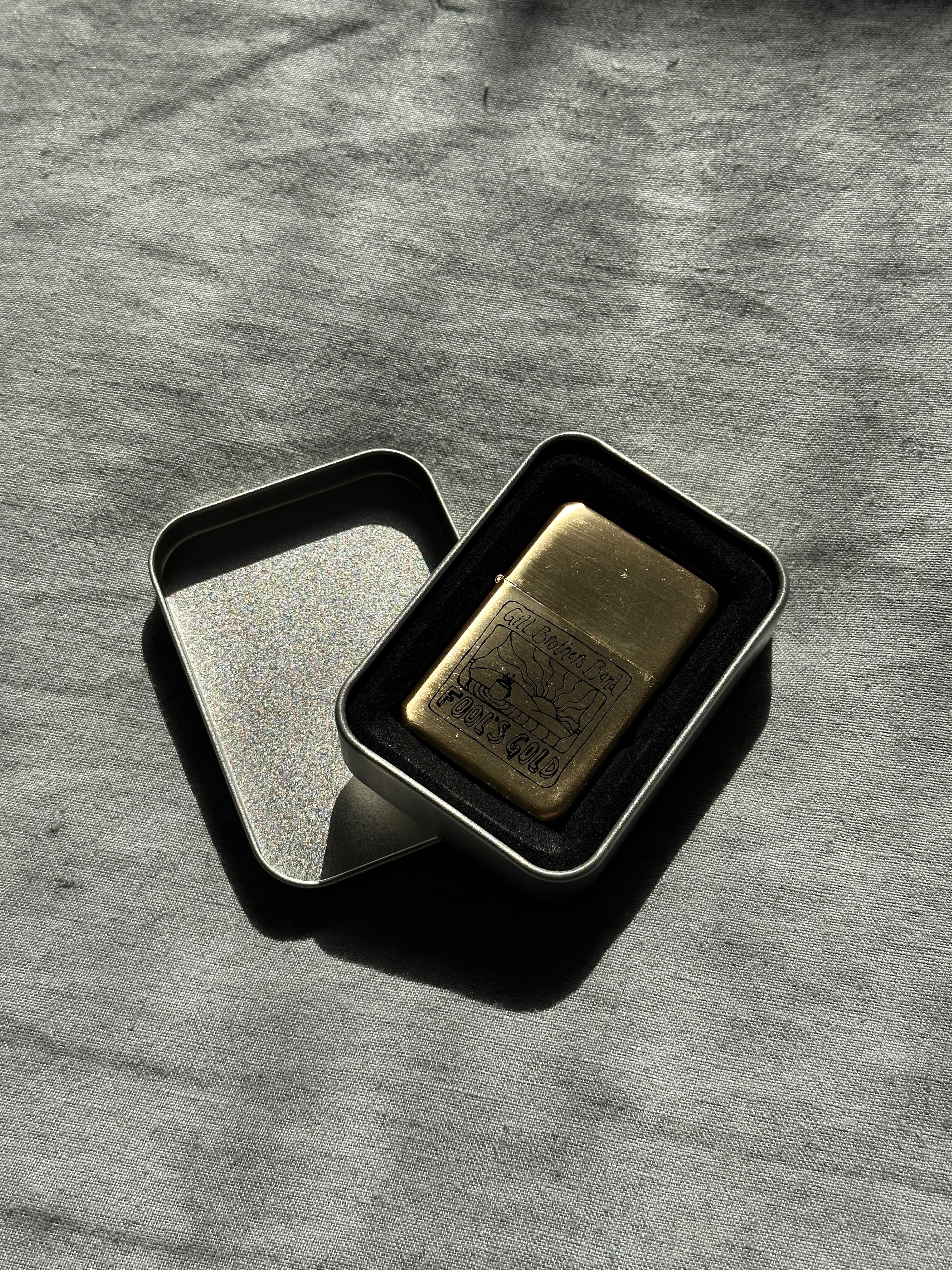 a gold lighter in a tin on a table