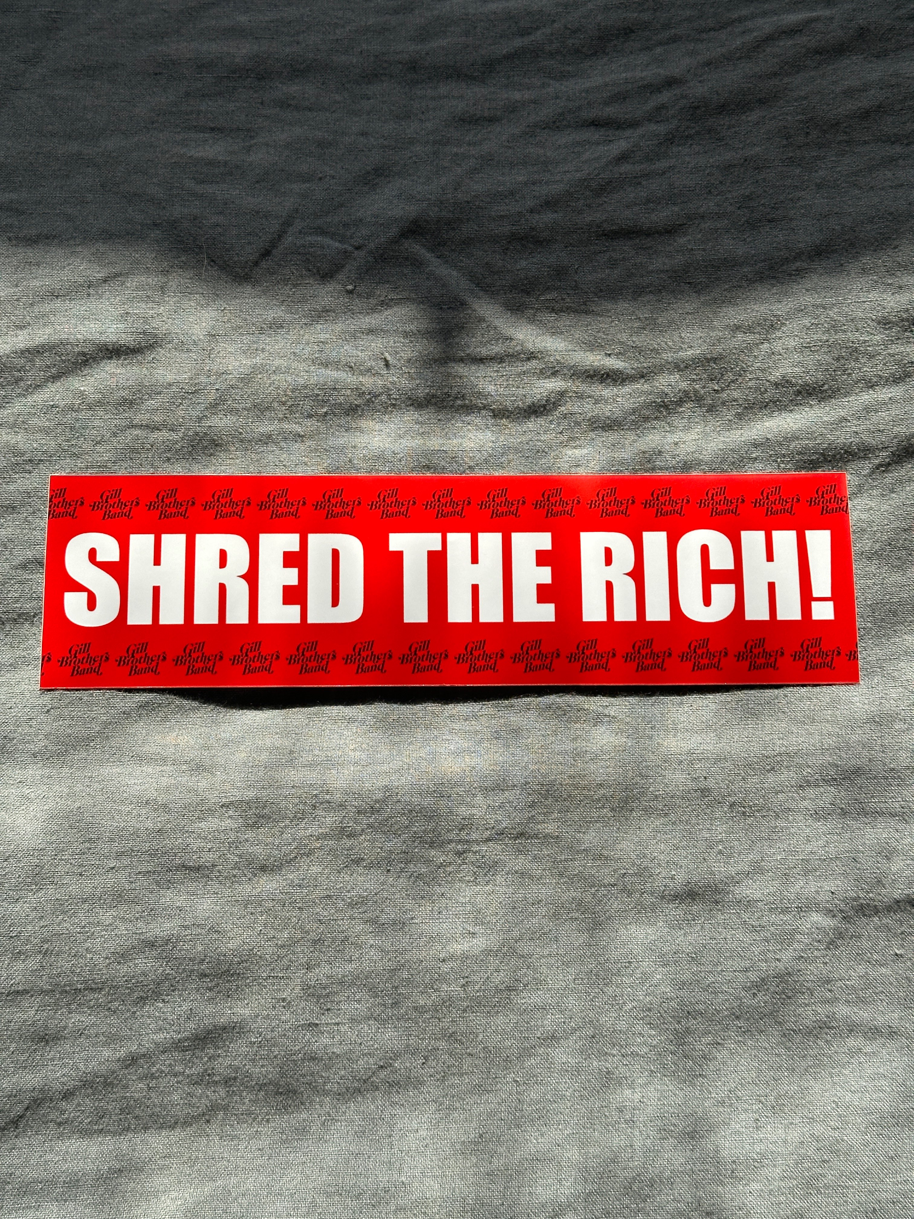 a red sticker that says shred the rich