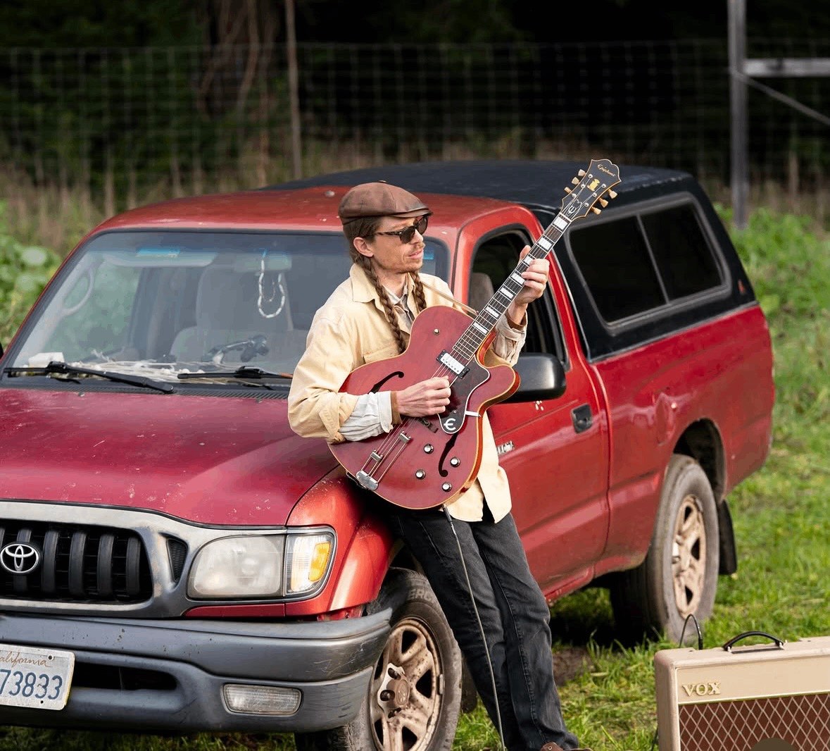 a man standing next to a red pickup truck