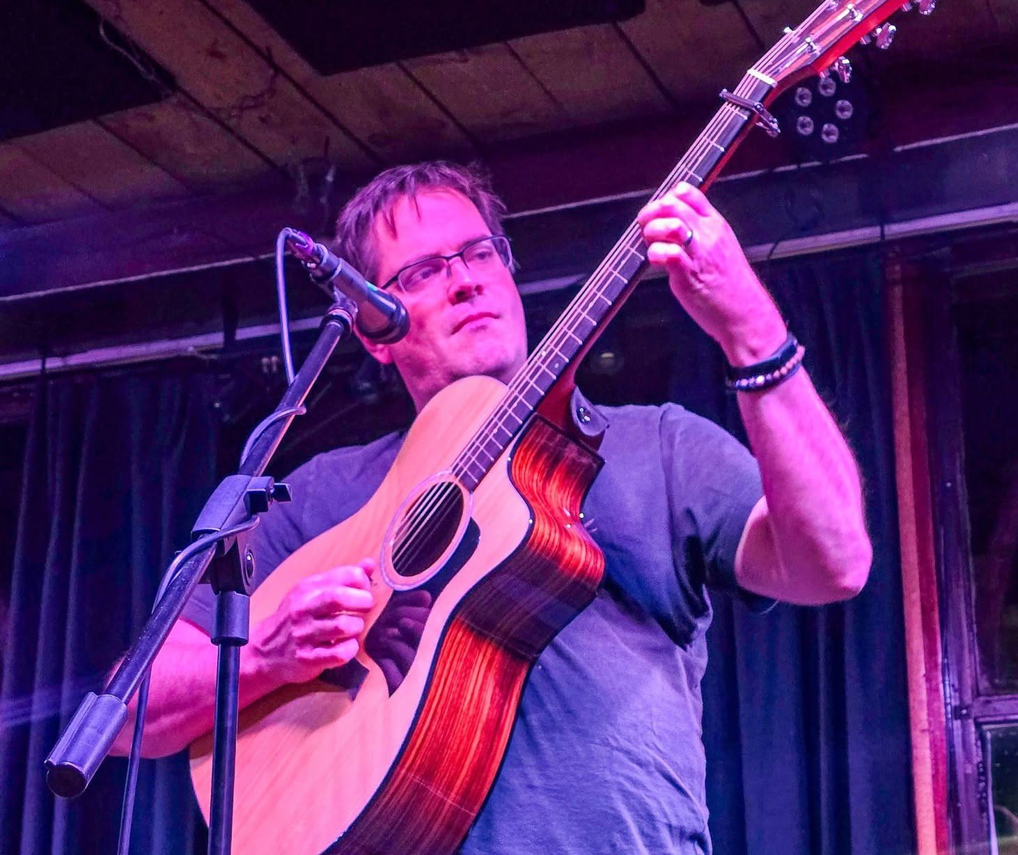 a man playing an acoustic guitar in front of a microphone