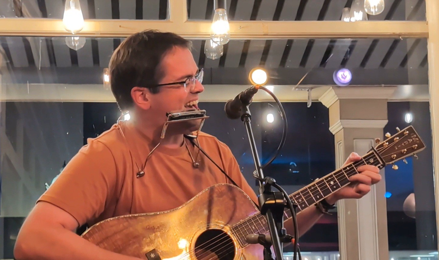 a man singing into a microphone while playing an acoustic guitar