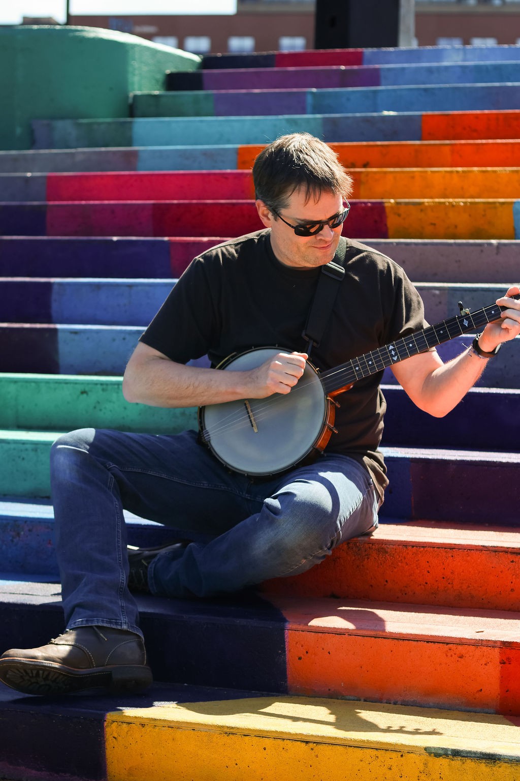 a man playing a banjo on colorful steps