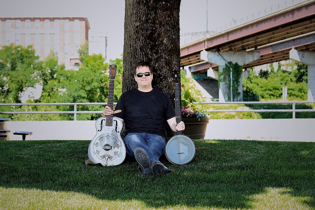 a man sitting under a tree with a guitar