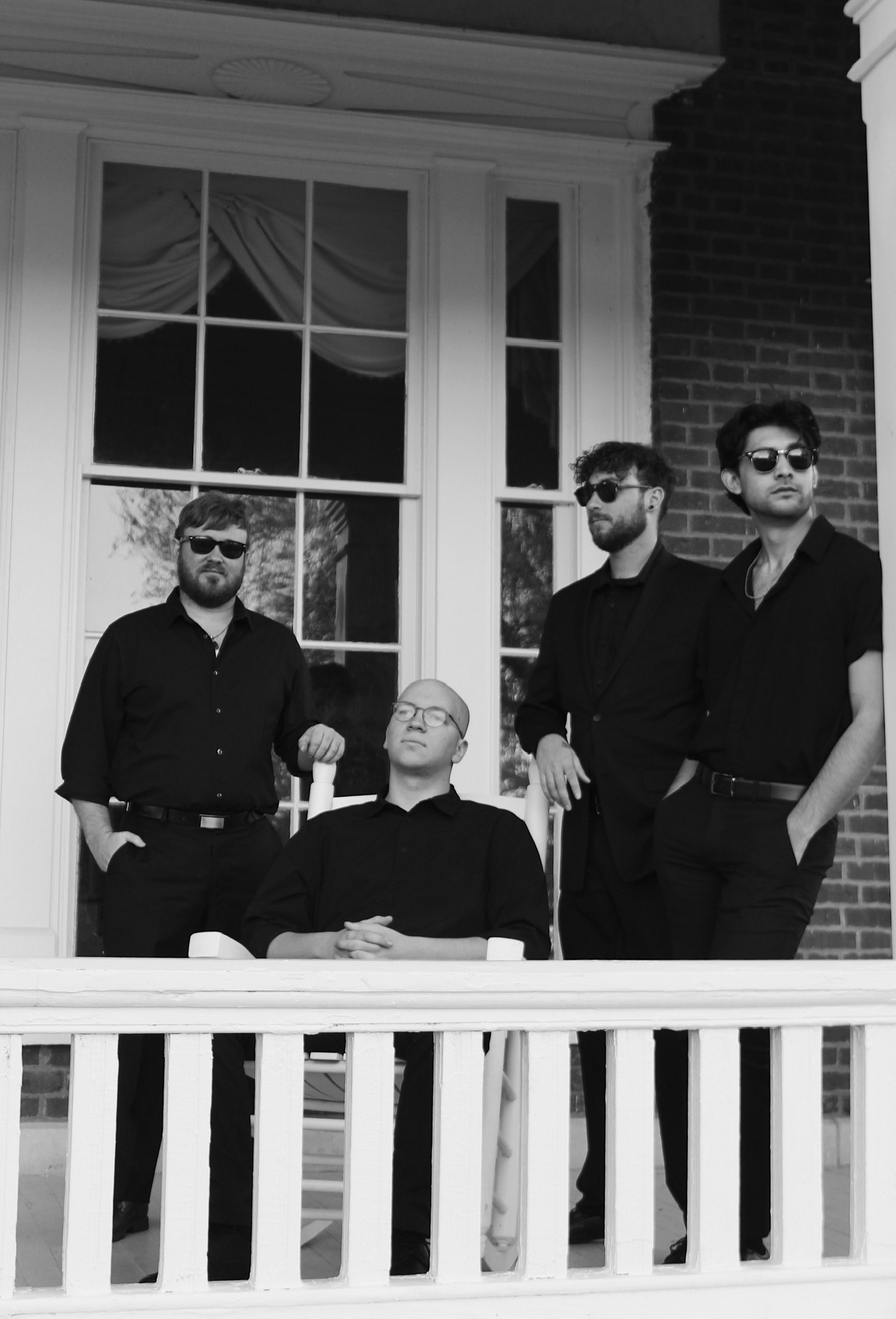 a black and white photo of a group of men on a porch