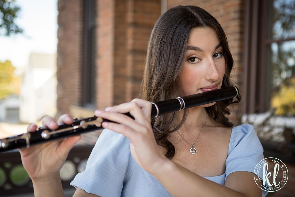 a girl playing a flute in front of a brick building