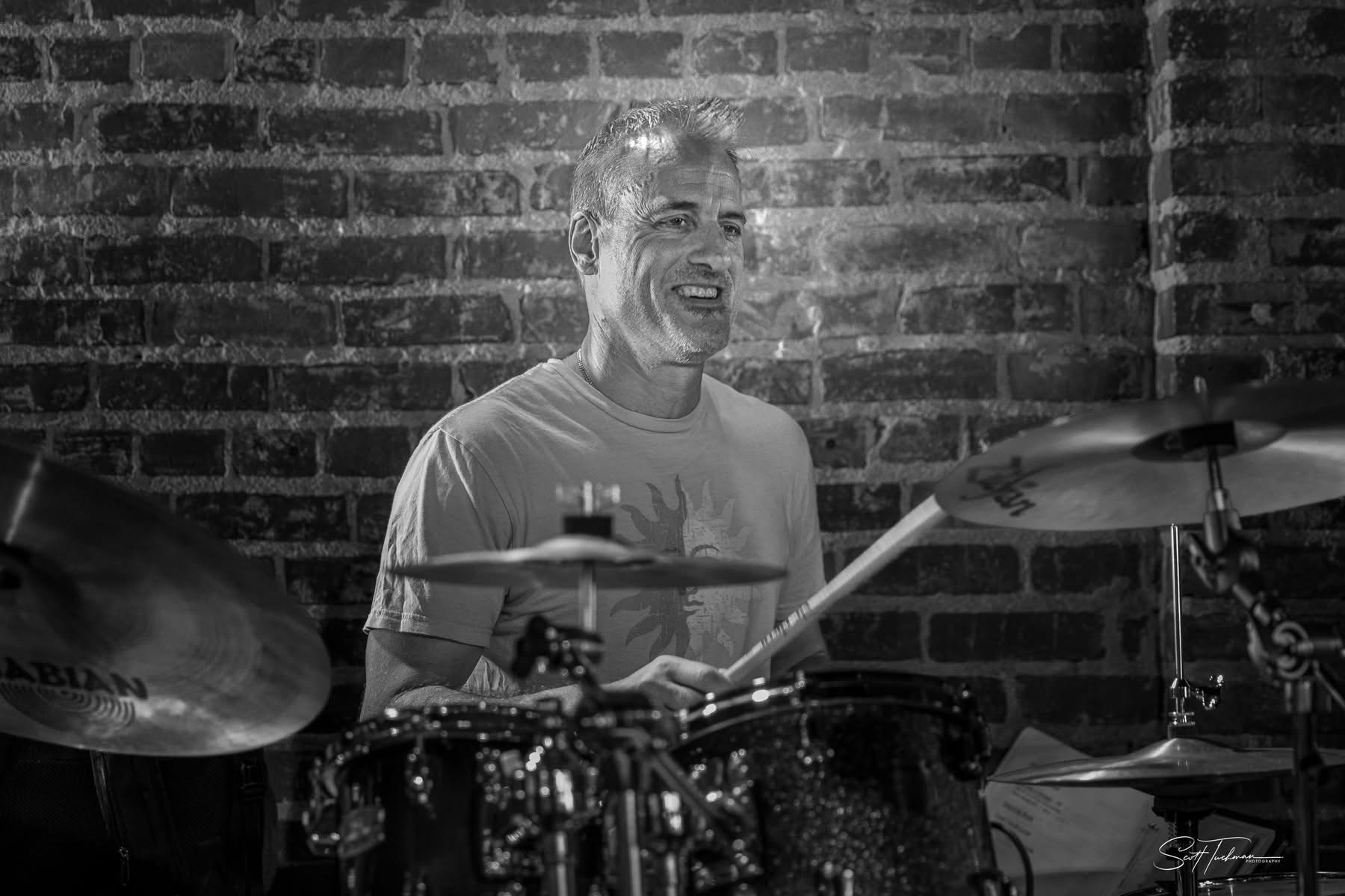 a black and white photo of a man playing drums
