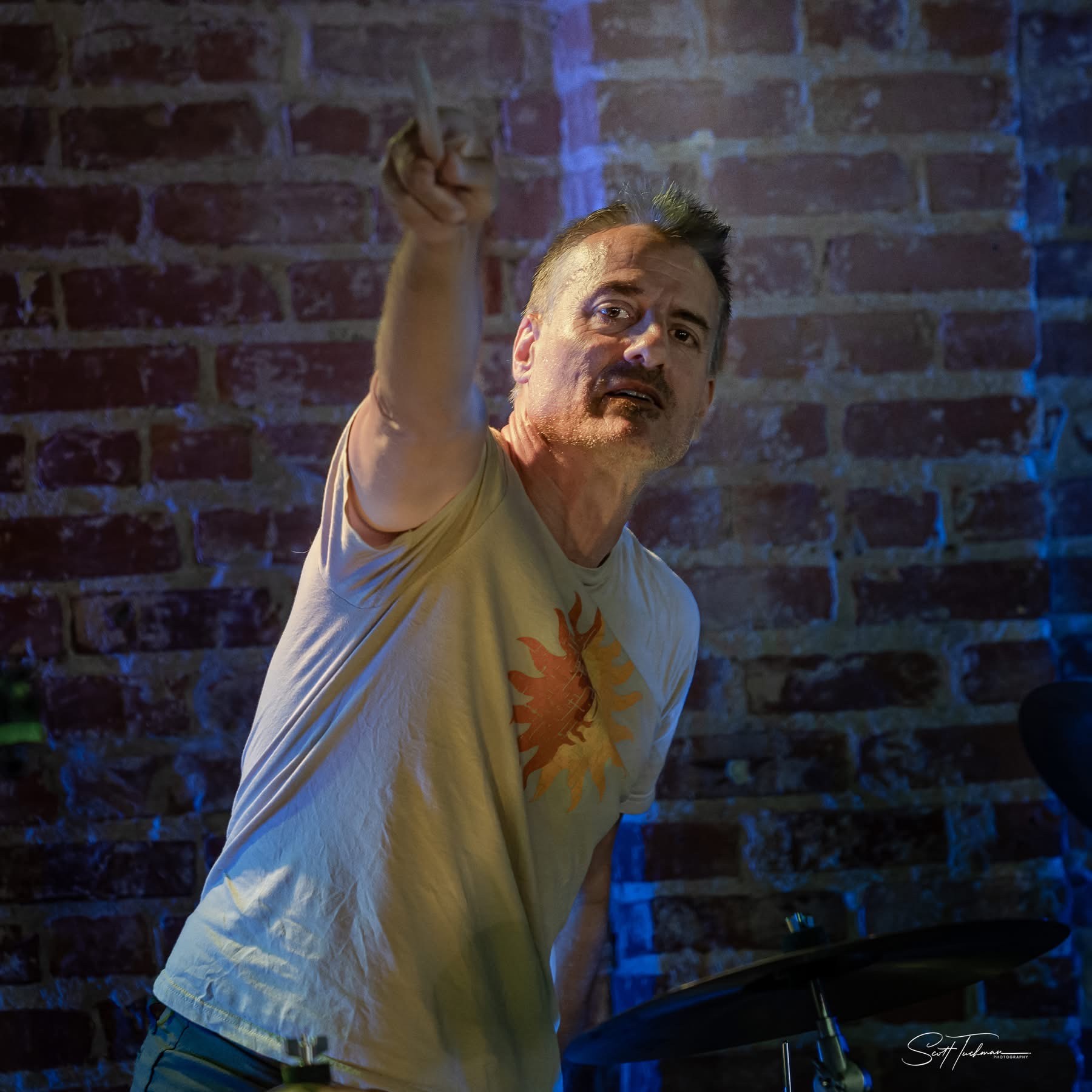 a man is playing drums in front of a brick wall