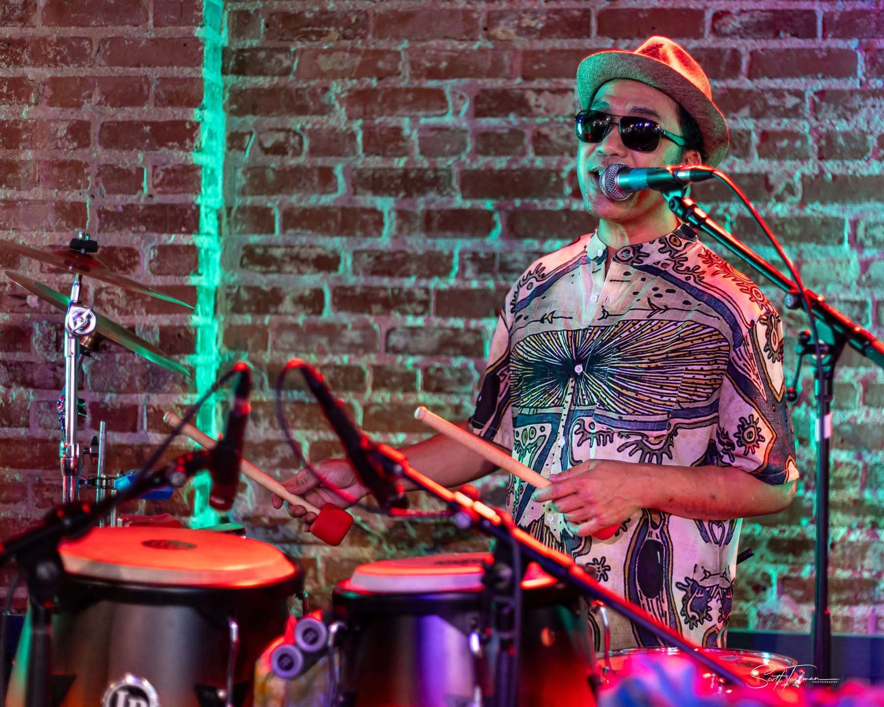 a man playing drums in front of a brick wall
