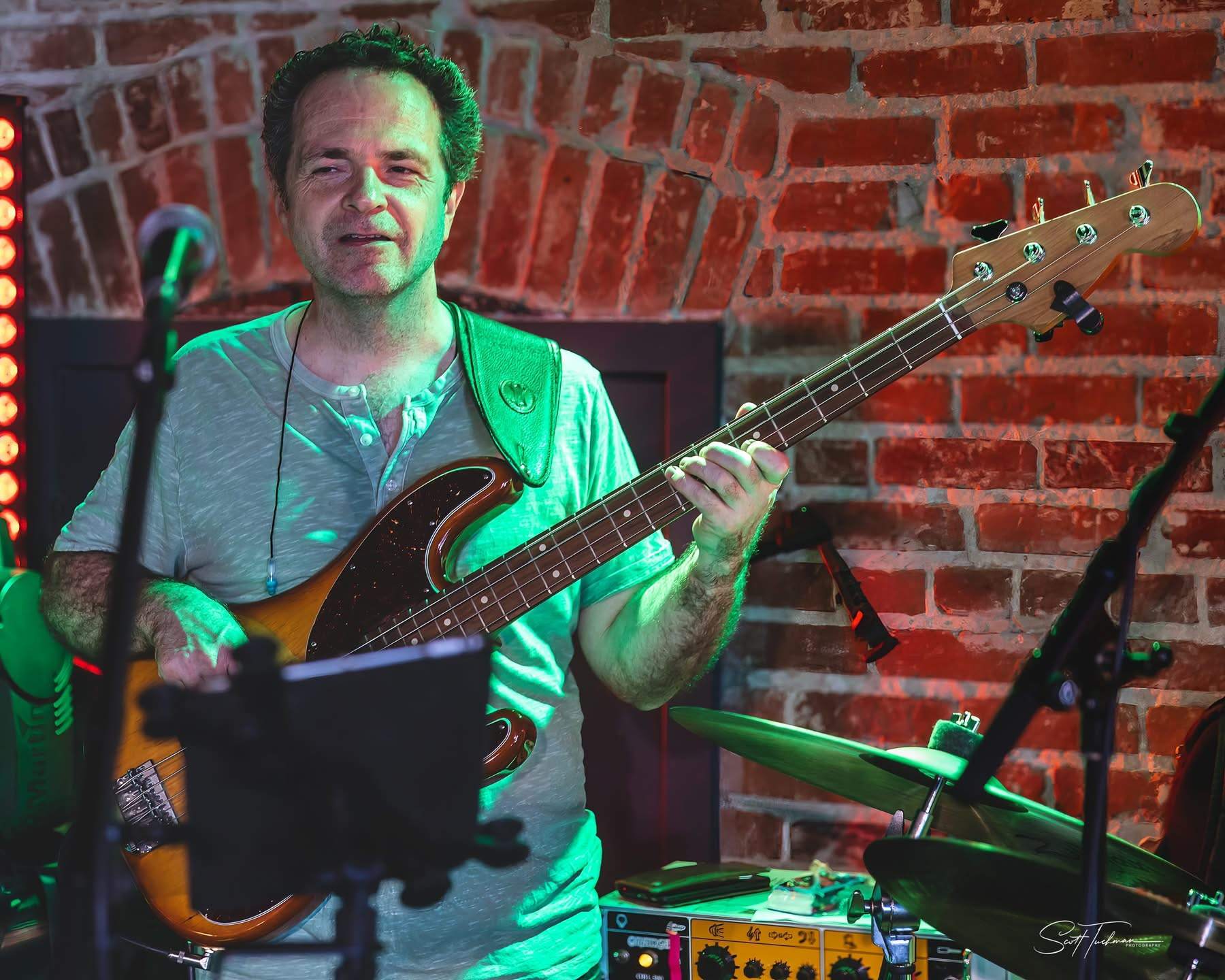 a man playing a bass in front of a brick wall