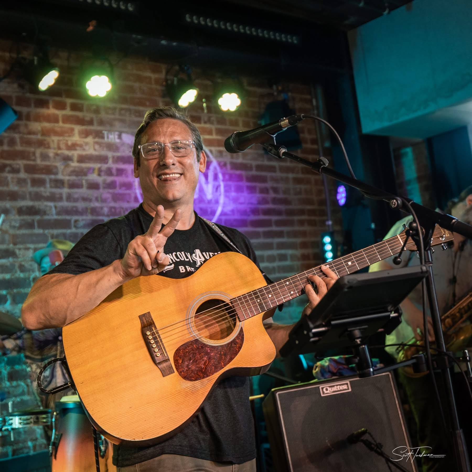 a man playing an acoustic guitar in front of a microphone