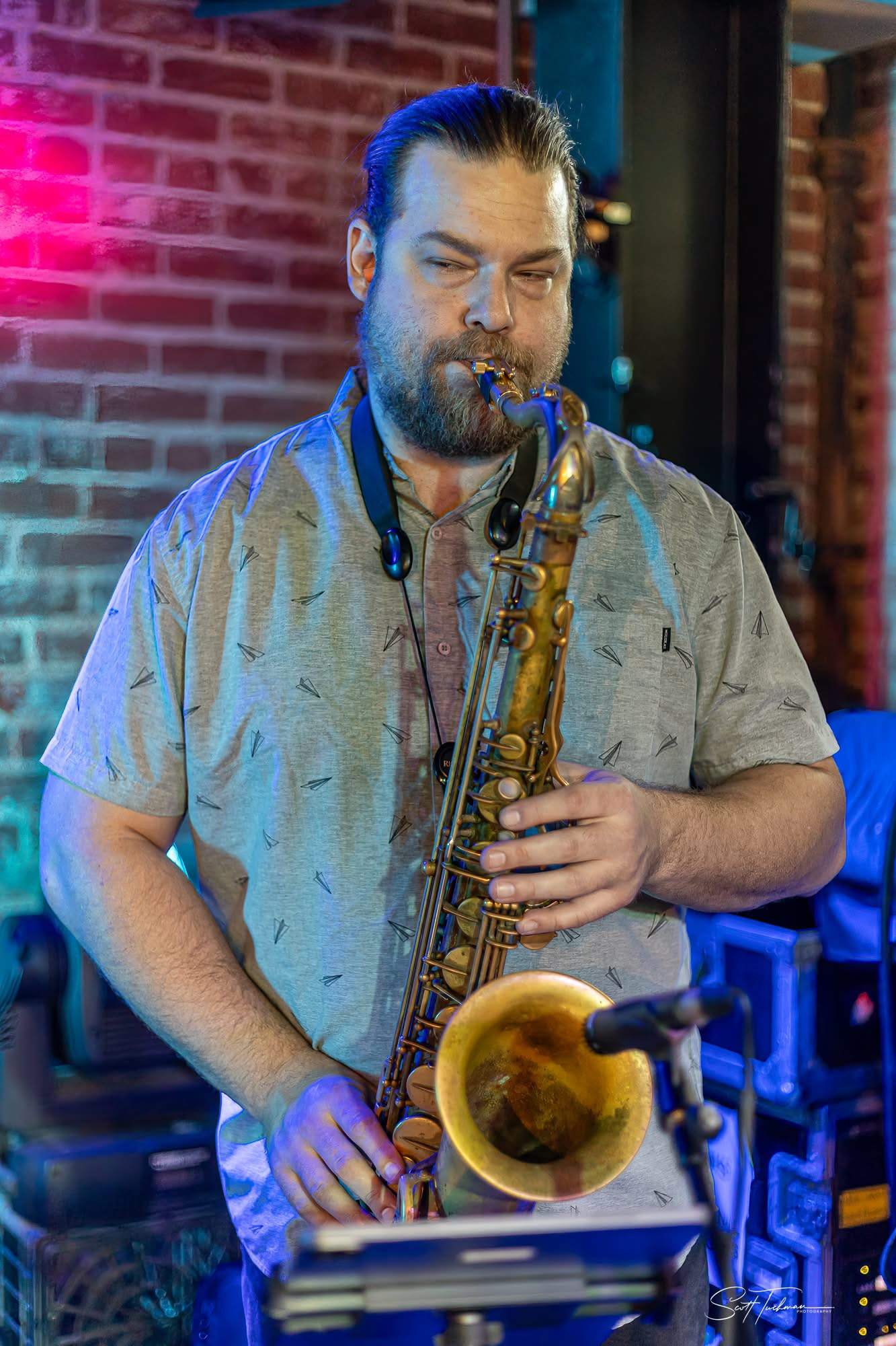 a man playing a saxophone in front of a brick wall