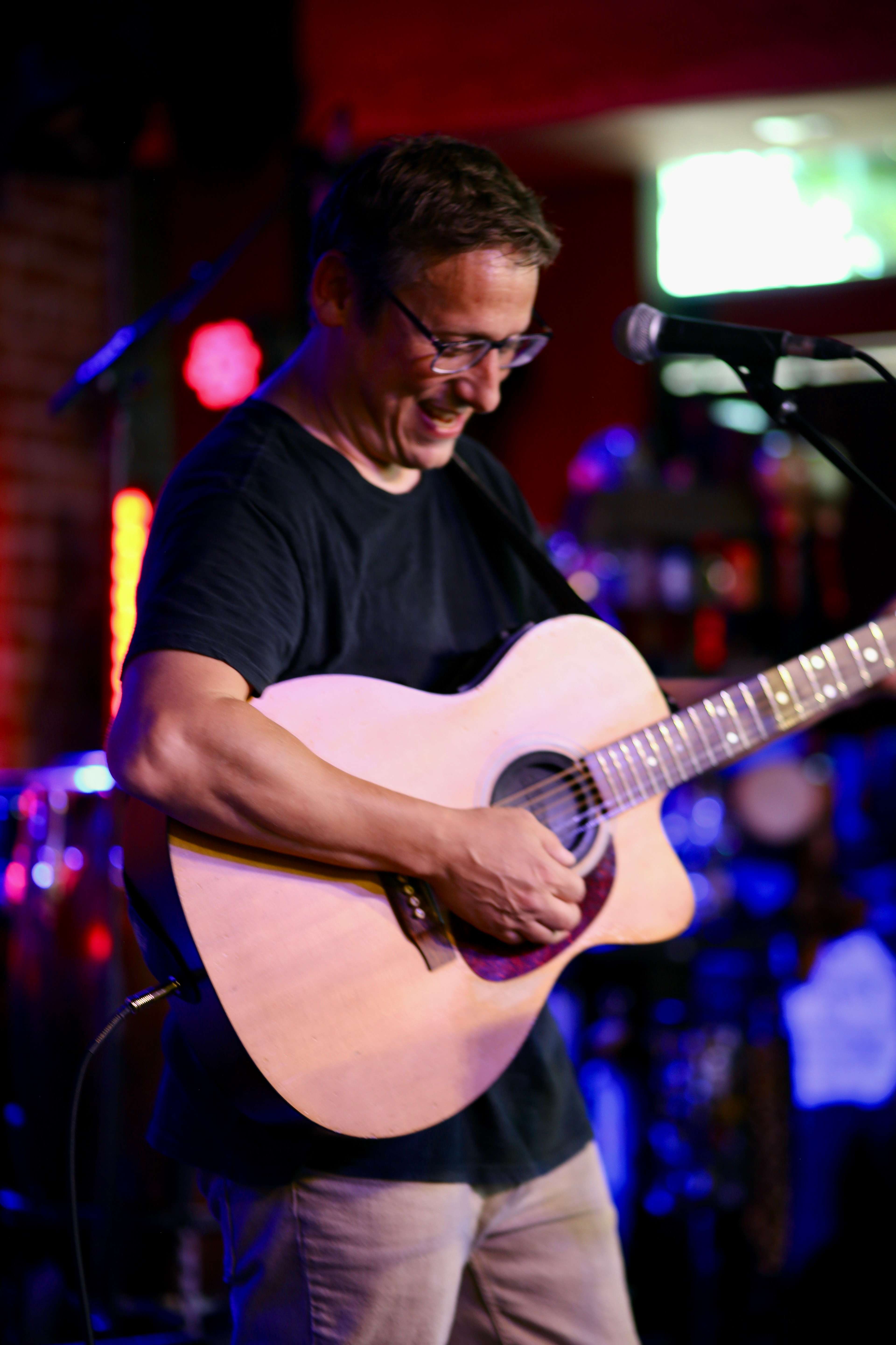 a man playing an acoustic guitar in front of a microphone