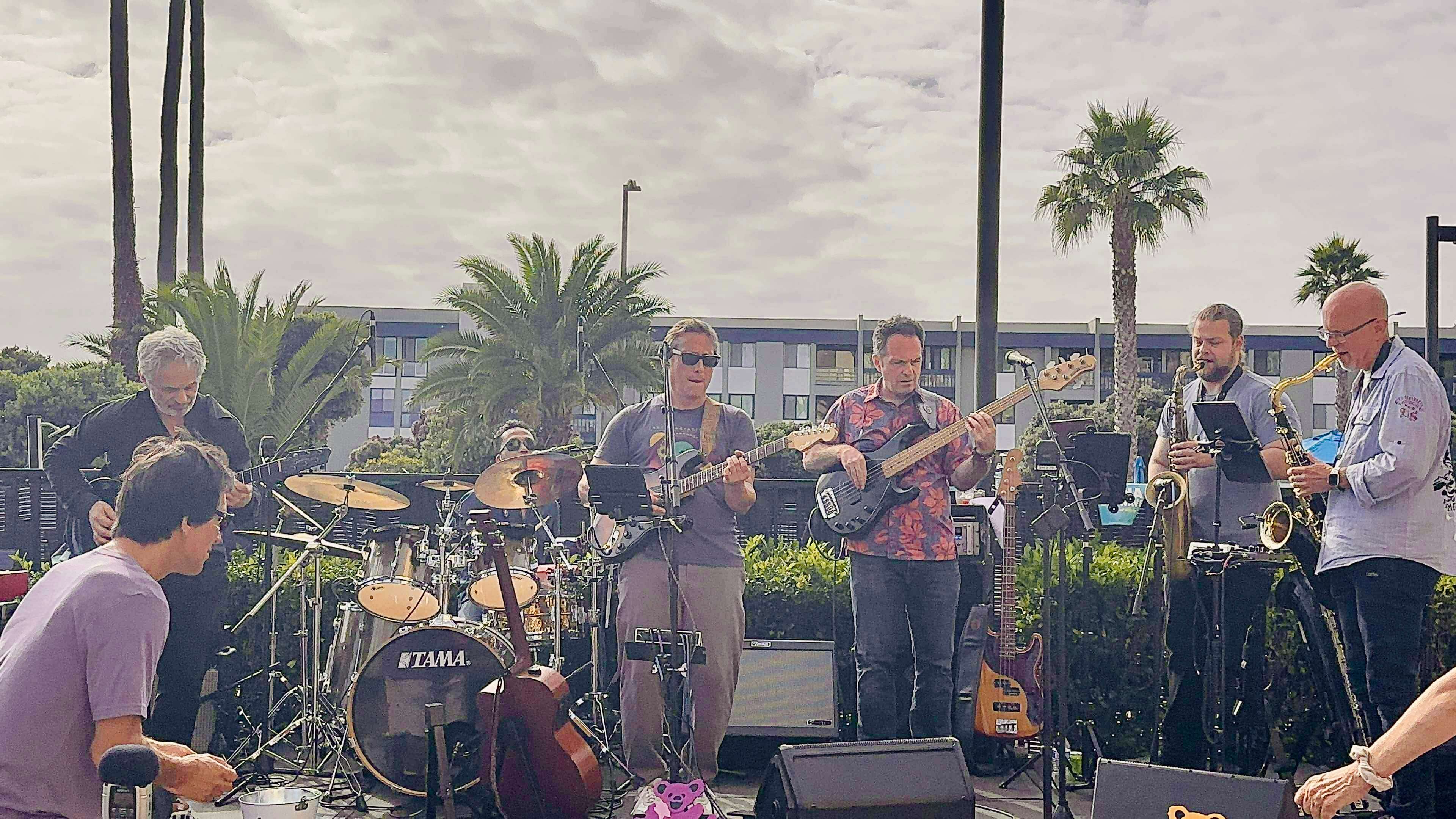 a group of people playing music on a stage in front of palm trees