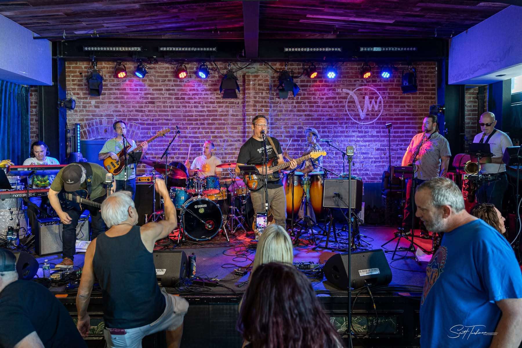 a band performs on stage in front of a brick wall