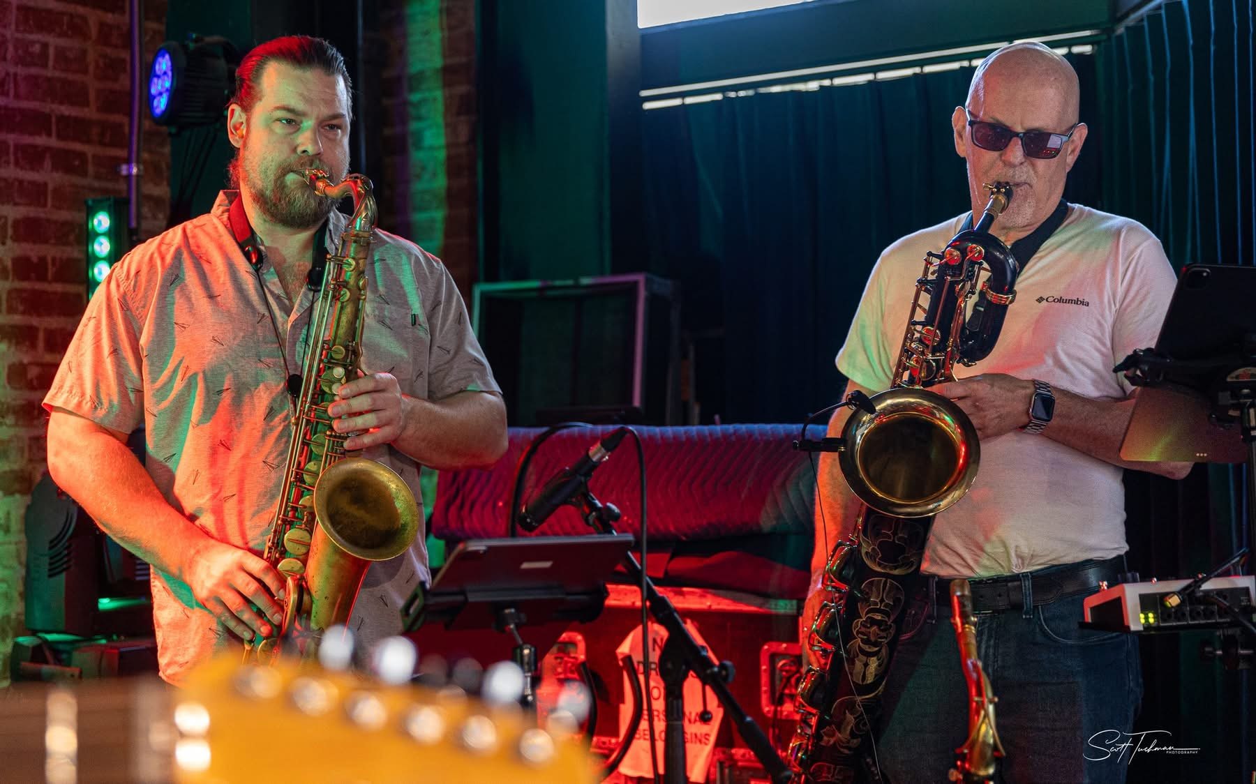 two men playing saxophones in a bar
