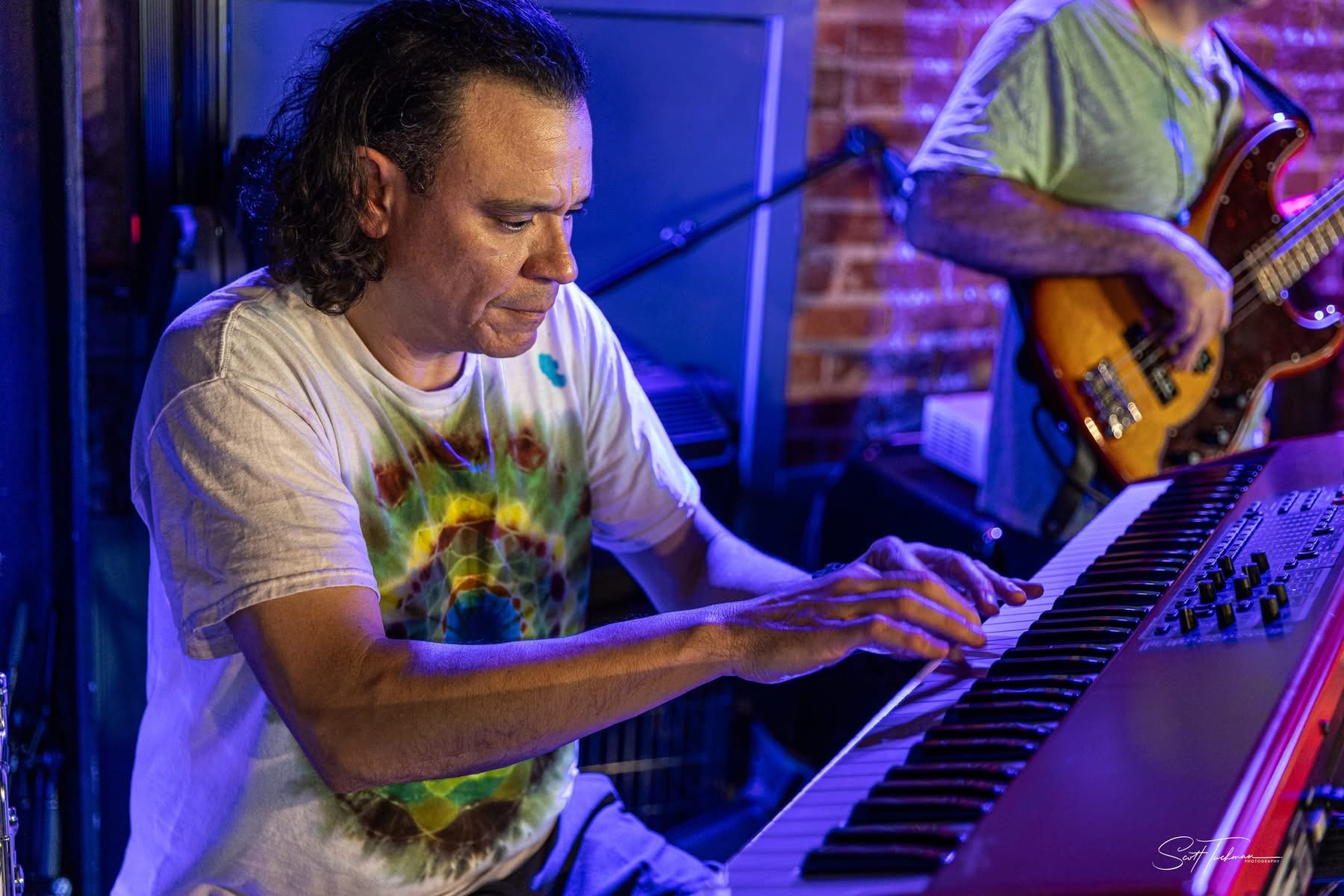 a man with long hair playing a keyboard