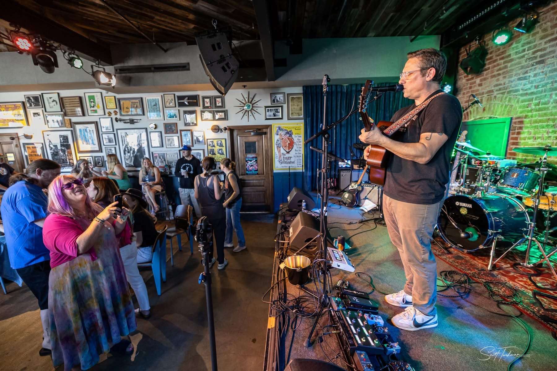 a man playing an acoustic guitar in front of a crowd